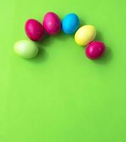 Green background and colored Easter eggs in the form of a rainbow. Copy space for text. photo