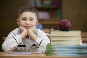 Schoolboy at the desk. Boy in the classroom with books and an apple. Secondary school. Back to school. photo