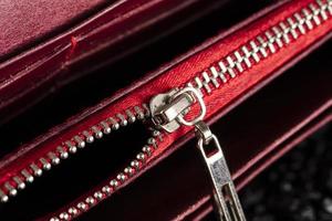 An open zipper on a red leather item or wallet. photo