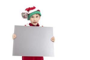 gracioso chico vestido como Papa Noel claus sostiene un blanco bandera. foto