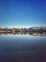 View of lake and houses on the shore in the early morning with blue sky photo