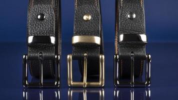 Group of black leather belts on a blue background. photo