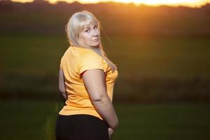 retrato de una mujer europea de mediana edad en chándal, posando para la cámara, relajándose. emocionada mujer con sobrepeso en chándal de moda descansando después de hacer ejercicio. foto