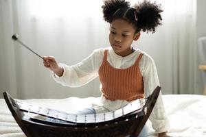 A little girl plays the xylophone in a music class. The child learns to play the xylophone photo