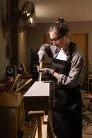 atractivo hembra carpintero utilizando algunos poder herramientas para su trabajo en un carpintería foto