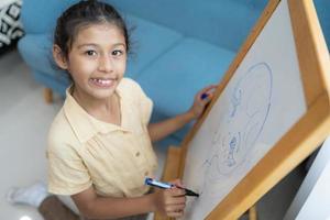 Little girl writing on empty whiteboard with a marker pen photo