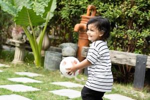 linda pequeño chico jugando fútbol con pelota al aire libre en fútbol campo foto