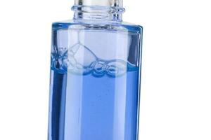 Part of a bottle with blue cosmetic liquid close-up on a white background. photo