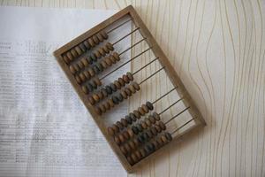 Vintage wooden abacus on the background of a sheet with numbers and calculations. photo