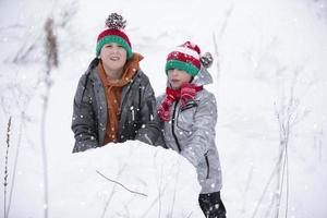 Two boys are playing in the snow. Children sculpt from snow. Play on a winter day in nature. photo