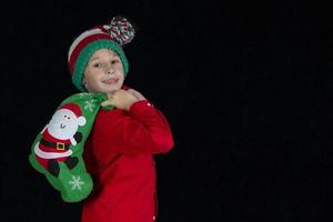 Little boy with a Christmas present on a black background. photo