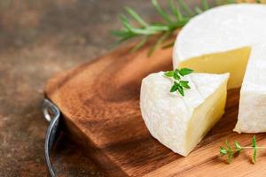 rebanado queso Camembert queso con tomillo en madera lámina. queso Camembert es un húmedo, suave, cremoso, foto