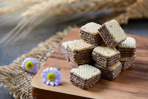 square chocolate wafer biscuits on wood plate with flower photo