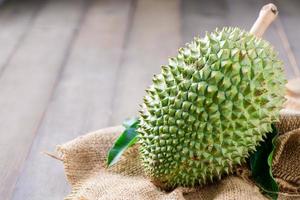 fresh Puangmanee durian on sack and wood background, It's a small durian. photo
