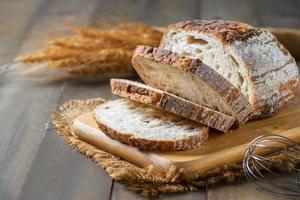 rebanado de masa fermentada un pan en madera tablero en madera fondo, hecho en casa panadería foto