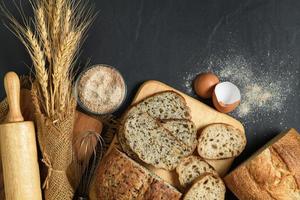 slide multi grain sourdough bread and sliced Baguette with Whole Wheat Flour on black stone background, photo