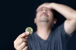 Man holding bitcoins and feel stressed because of the loss of online bitcoin trading photo