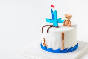 boat and doll bear fondant on vanilla cake on white background, photo