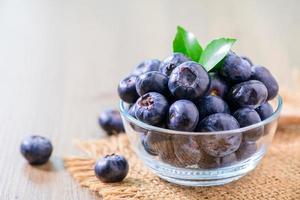 Fresh organic blueberries in a glass bowl on wood background, photo