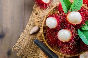 Top view of Fresh Rambutan fruits with leaves on bamboo basket isolated on wood background. photo