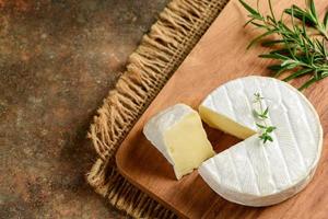 Camembert Cheese with thyme on wood plate. Camembert is a moist, soft, creamy, photo