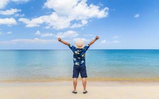 Young Asian man raise his hands up by the sea, vacation time, photo