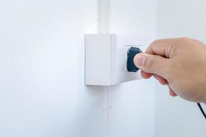 Closeup of a man's hand inserting an electrical plug into socket. photo