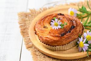 Danish Pastry with Raisins on wood plate and white wood background, photo