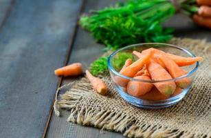 Baby carrots in glass cup on wood background, High Beta Carotene and help the body have immunity photo
