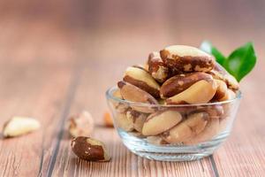 Bowl with tasty Brazil nuts on sack and space for text on  wooden background, photo
