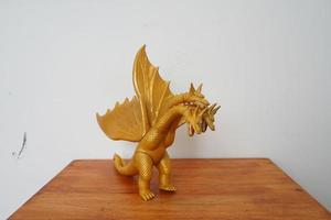 golden dragon ghidorah isolated on white background. On wooden table photo