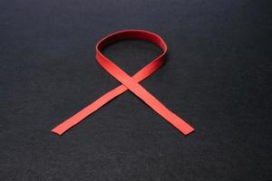 Aids awareness red ribbon isolated on black background photo