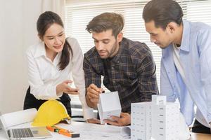Construction of Engineer, architect businessman, woman making on 3D model house building in office together, meeting plan working with partner team colleagues on blueprint, discussing design project photo