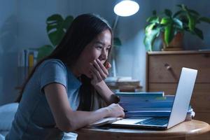 Wfh, asian young student woman yawning covering mouth, study online sitting on desk at home, doing homework connecting to internet on laptop computer, studying late at night, learning and education. photo