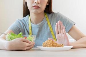 dieta, dieta asiático joven mujer o niña empujar afuera, negar frito pollo, basura comida y escoger Fresco vegetales ensalada de bol, comer comida para bueno saludable, salud cuando hambriento. hembra peso pérdida personas foto