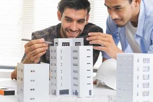 Construction of Engineer, architect businessman, man hand making on 3D model house building in office together, meeting plan working with partner team colleague on blueprint, discussing design project photo