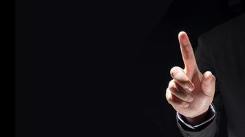 Businessman hand touching virtual screen on black background photo