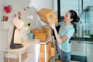 A young woman owner of a small e-commerce business is packing items into the mail box. photo