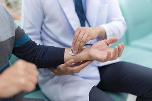 Physician listening senior man on arm through stethoscope, Doctor introducing treatment to patient photo