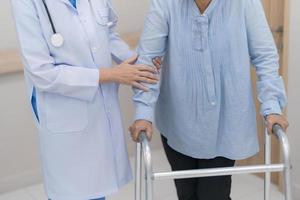 Doctor introducing treatment to patient, Physician supporting senior woman on the arm and walking outside. photo