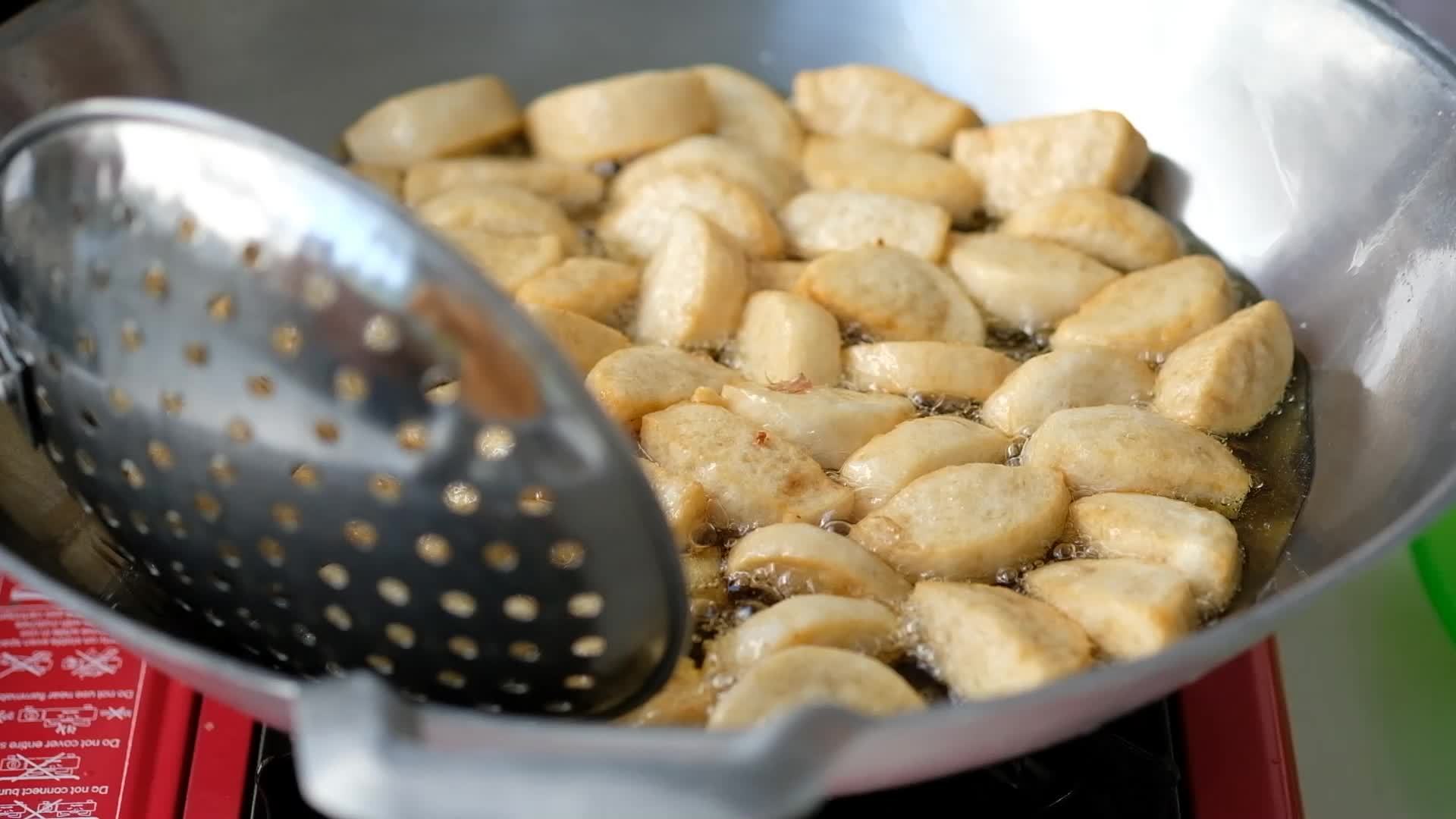 A frying pan with hot oil is frying meatballs in a pan for appetizers