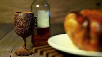 Brandy di legno bicchiere e liquore bottiglia con sfocatura torrefazione pollo rotante video