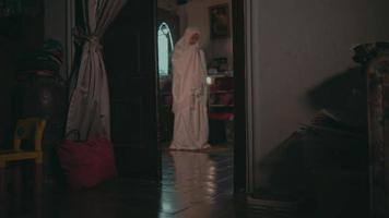 un' musulmano donna è preghiere per indossare un' bianca musulmano vestito nel un' camera pieno di merce video