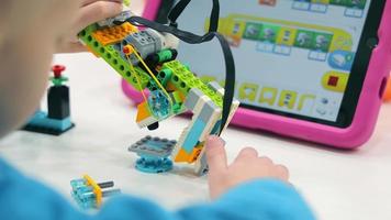 as crianças brincam com lego e criam robôs programáveis. close-up de robótica. video