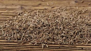 Aromatic cumin dry seeds texture on a wooden table video
