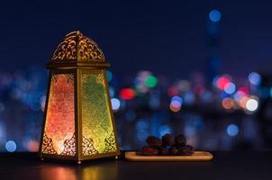 Lantern and small plate of dates fruit with night sky and city bokeh light background for the Muslim feast of the holy month of Ramadan Kareem. photo