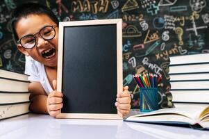 niño sentado y sosteniendo la pizarra en el aula foto