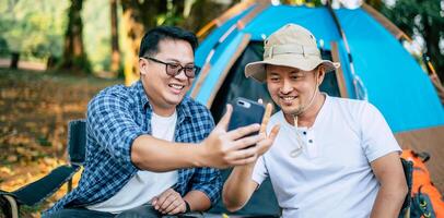 Portrait happy Asian man friends Making a video call with smartphone in camping photo