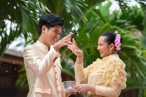 Young couple splashing water from bowl on Songkran festival photo