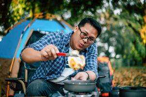 Portrait of Asian traveler man glasses frying a tasty fried egg photo